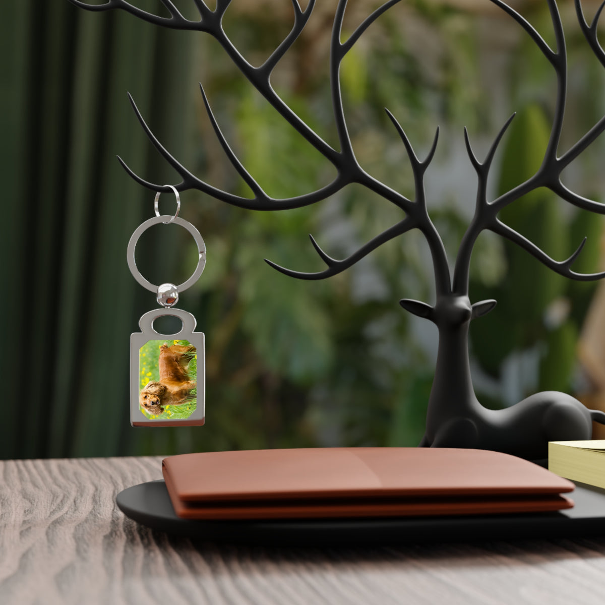 A silver metal keychain with a custom rectangular photo insert showing a golden retriever, hanging from a black antler-style decorative stand on a tabletop.